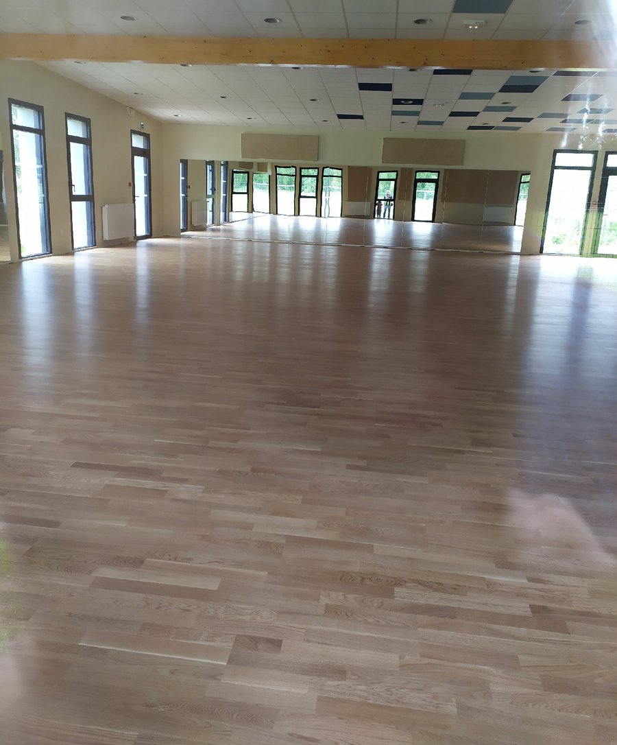 La grande salle de L'Académie à Barjouville : parquet en chêne, mur de miroirs, grandes baies vitrées et plafond aux poutres apparentes